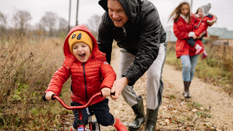 Dad pushing son on a bicycle